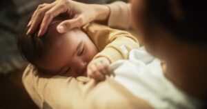 Mother and breastfeeding child viewed from slightly above and behind mother’s shoulder