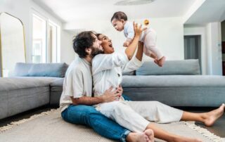 Happy parents playing with new baby at home
