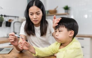 Mother checking sick child’s temperature with thermometer