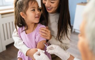 Parent holding child while they receive vaccination