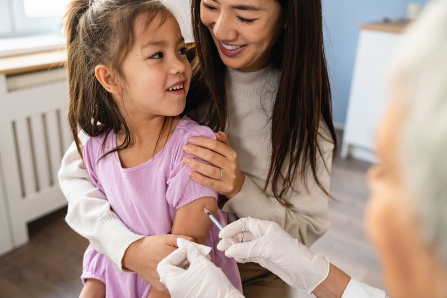 Parent holding child while they receive vaccination