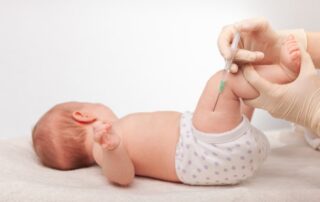 Small infant getting vaccine from doctor