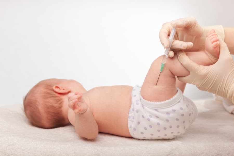 Small infant getting vaccine from doctor